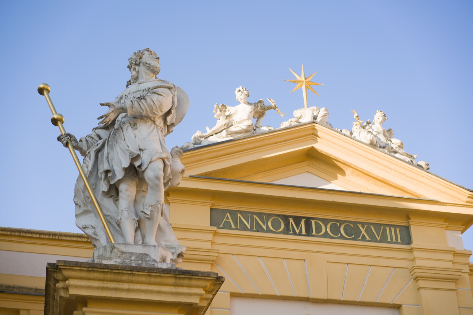 Statues atop the baroque facade of Melk Abbey against a blue sky
