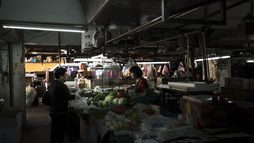 Vendors and produce inside a dim traditional wet market