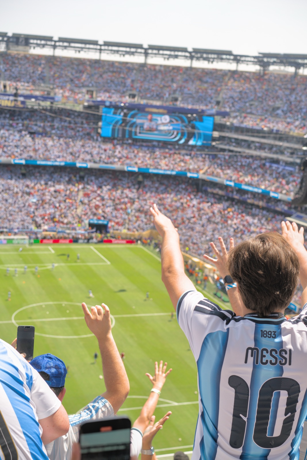 A fan in a Messi shirt spreading his arms toward the stands