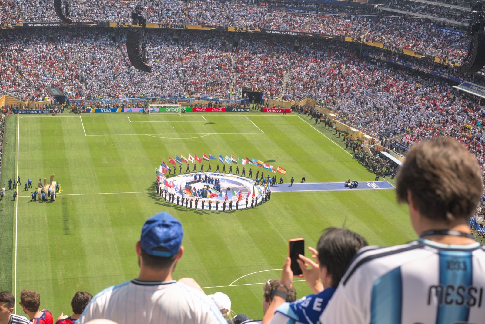 Players lining up on the pitch before kickoff, seen from the upper tier